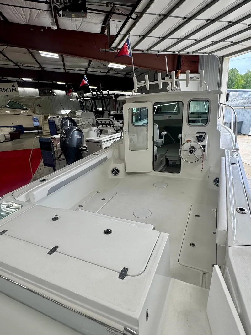 Slide: The Image of 2025 Parker 2420 Sport Cabin boat in showroom, featuring spacious deck and modern design. - 6