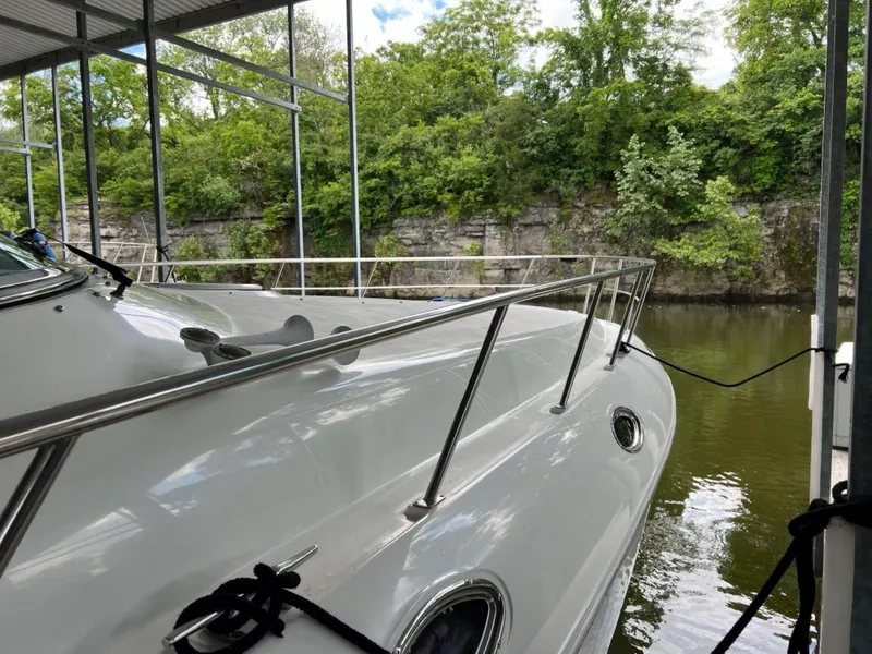 Slide: The Image of 2000 Cruisers Yachts 4270 Express docked by a lush, rocky shoreline. - 39