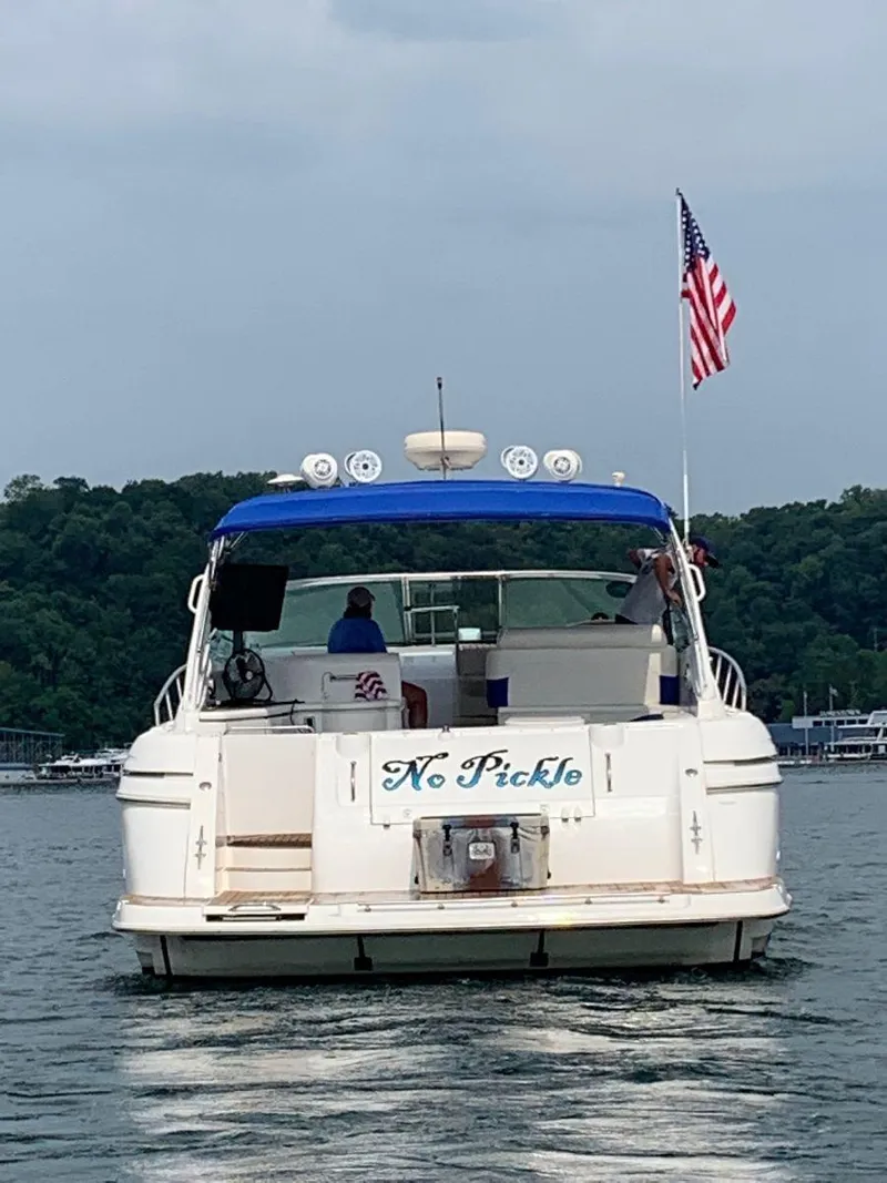 Slide: The Image of 2000 Cruisers Yachts 4270 Express boat on water, American flag, rear view. - 5