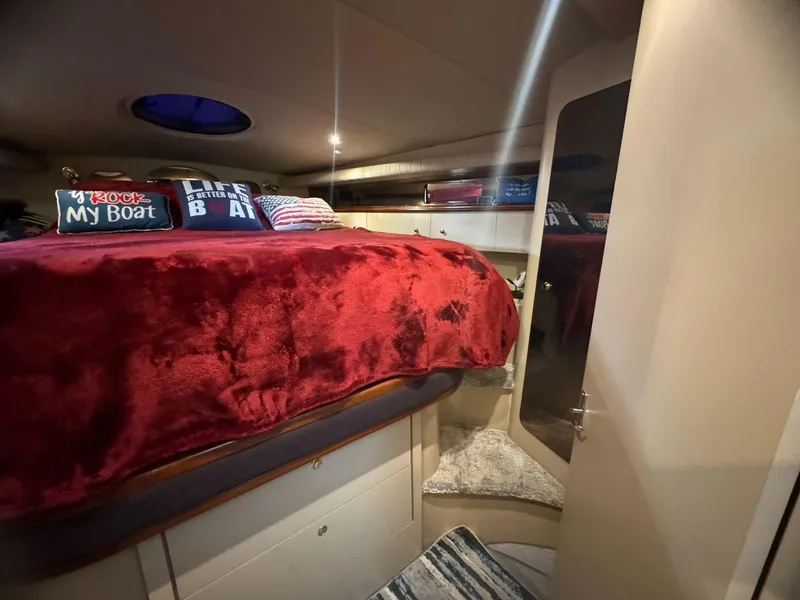 Slide: The Image of Cozy cabin interior of 2000 Cruisers Yachts 4270 Express with red bedding and nautical decor. - 19