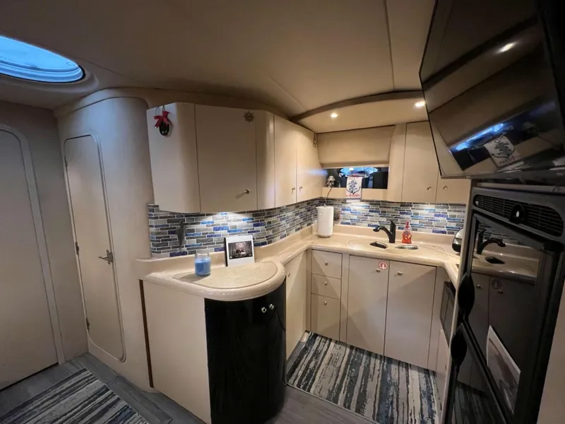 Slide: The Image of Interior of 2000 Cruisers Yachts 4270 Express, featuring modern kitchen with sleek cabinetry and lighting. - 26