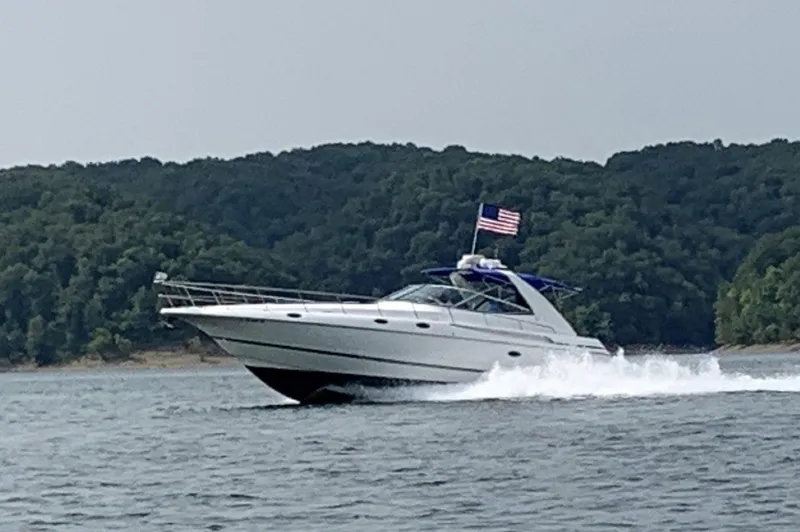 Slide: The Image of 2000 Cruisers Yachts 4270 Express cruising on a lake with forested hills in the background. - 3