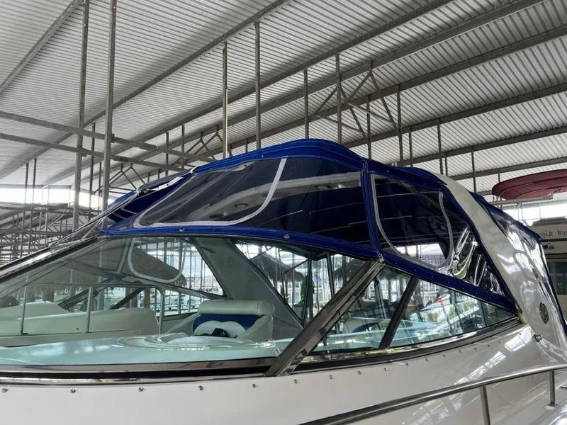 Slide: The Image of 2000 Cruisers Yachts 4270 Express with blue canopy in a covered marina. - 35