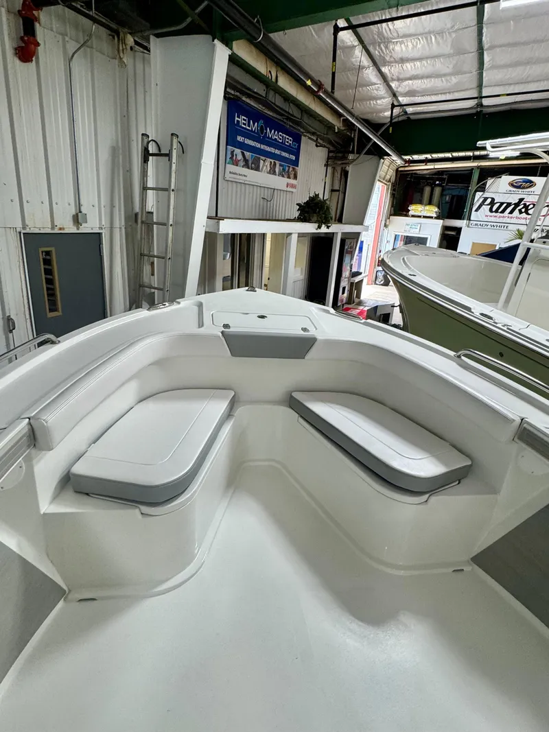 Slide: The Image of 2025 Parker 23SE Center Console boat interior with cushioned seating in a showroom. - 10