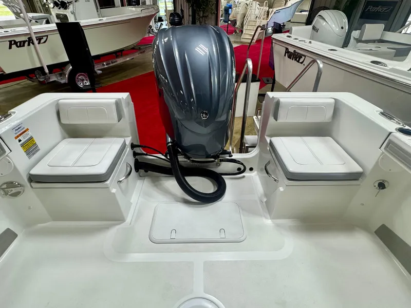 Slide: The Image of 2025 Parker 23SE Center Console boat interior with seating and engine, displayed indoors. - 7