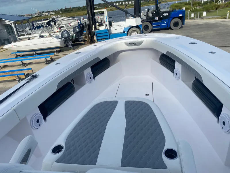 Slide: The Image of 2022 Front Runner 36 cc boat interior with cushioned seating and cup holders at a marina. - 19