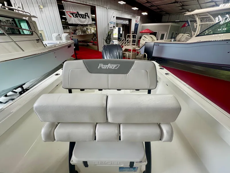 Slide: The Image of 2025 Parker 23SE Center Console boat interior with cushioned seating in a showroom. - 8