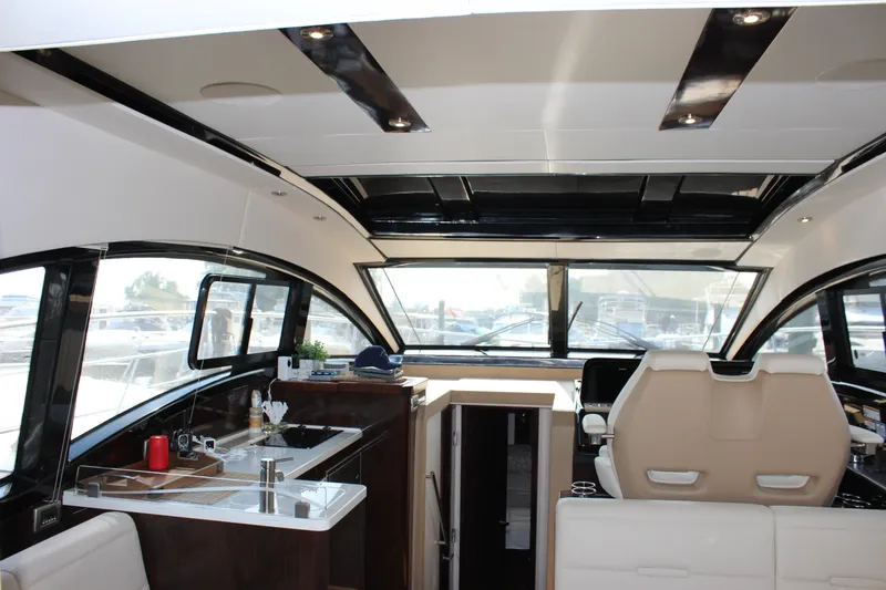 Slide: The Image of 2017 Sea Ray Sundancer 400 interior with modern helm, kitchenette, and panoramic windows. - 46