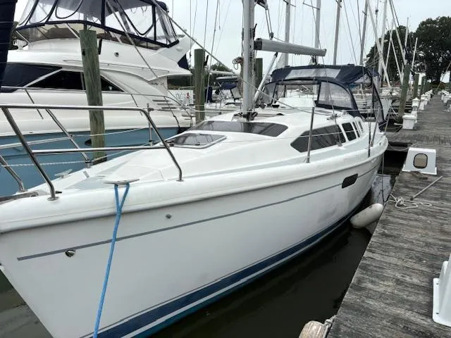 Slide: The Image of 2001 Hunter 340 sailboat docked at marina, white hull, blue trim, and covered cockpit. - 1