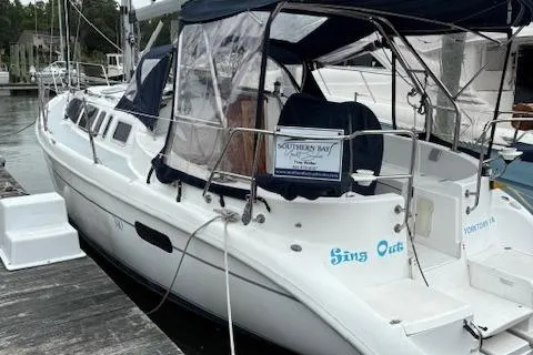 Slide: The Image of 2001 Hunter 340 sailboat docked, featuring a white hull and blue canopy. - 36