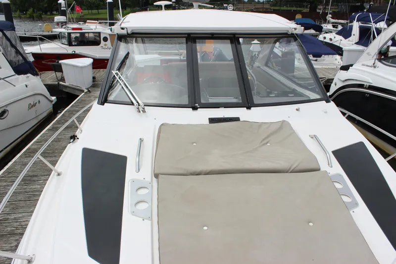 Slide: The Image of 2014 Regal 35 Sport Coupe boat docked, featuring a spacious sunpad and sleek design. - 17