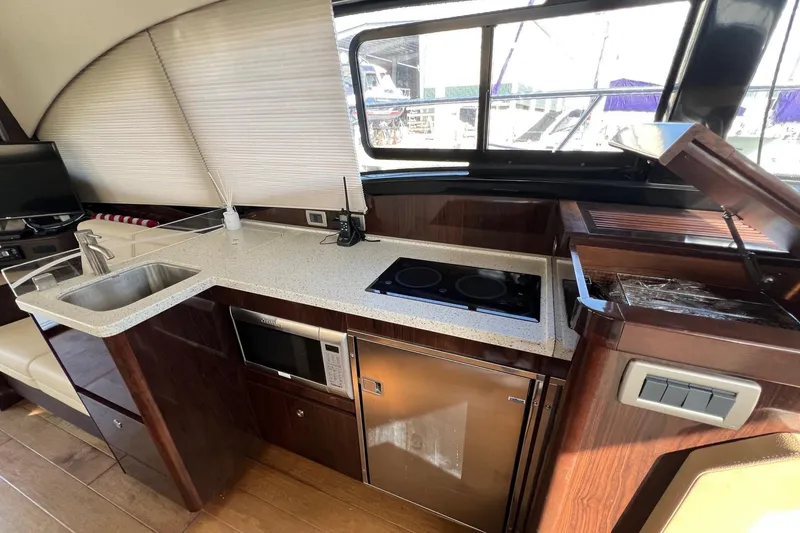 Slide: The Image of 2017 Sea Ray Sundancer 400 yacht kitchen with sink, stove, microwave, and fridge. - 39
