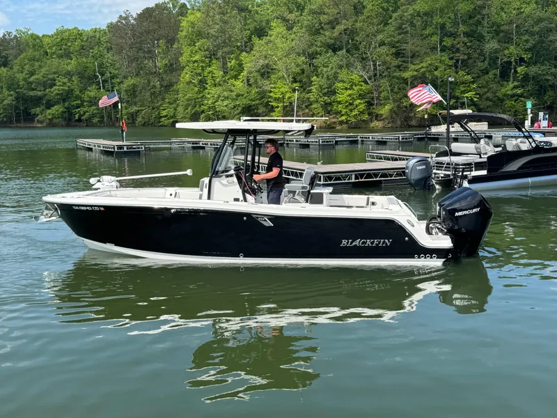 Slide: The Image of 2023 Blackfin 252 CC boat on a lake with American flags in the background. - 1