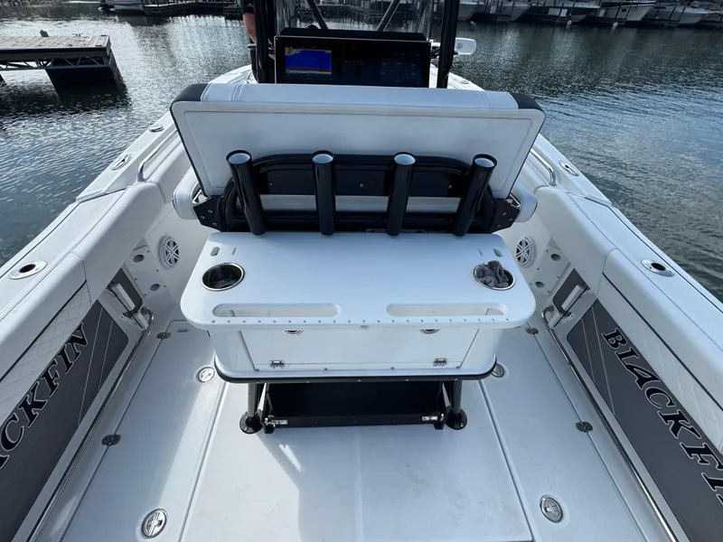 Slide: The Image of 2023 Blackfin 252 CC boat interior with rod holders and seating, docked on calm water. - 12