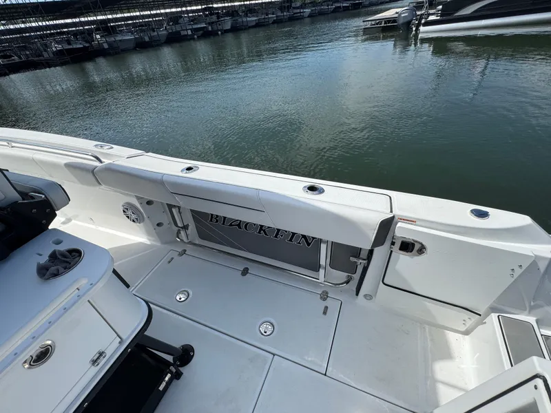 Slide: The Image of 2023 Blackfin 252 CC boat interior with seating and storage, docked by calm water. - 15