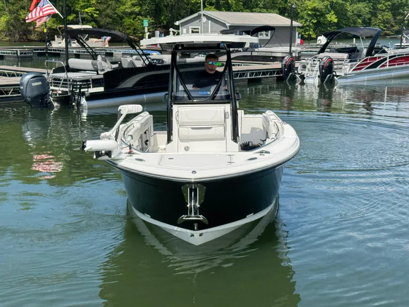 Slide: The Image of 2023 Blackfin 252 CC boat navigating a marina with docks and other boats. - 2