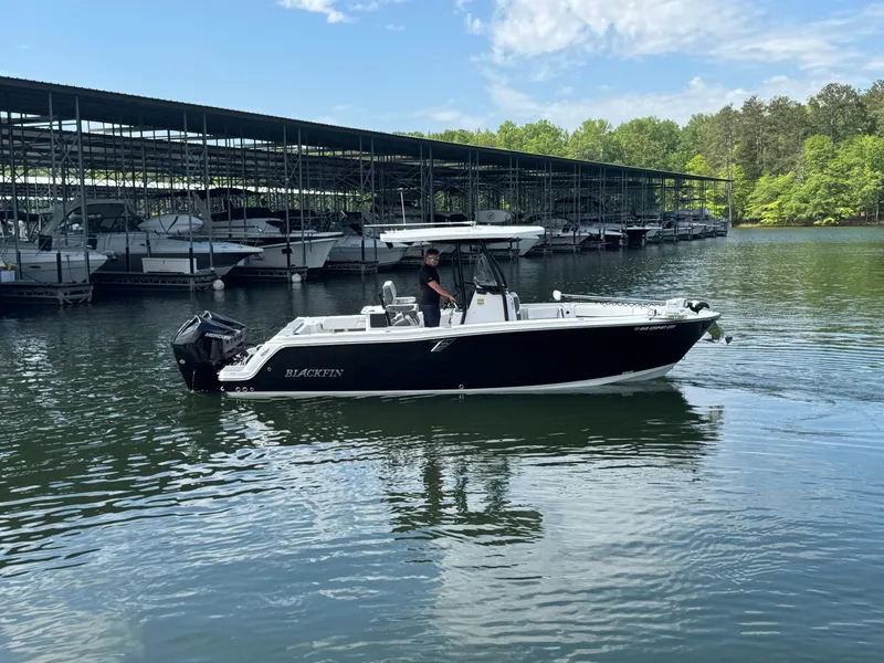 Slide: The Image of 2023 Blackfin 252 CC boat cruising near marina with covered docks. - 4