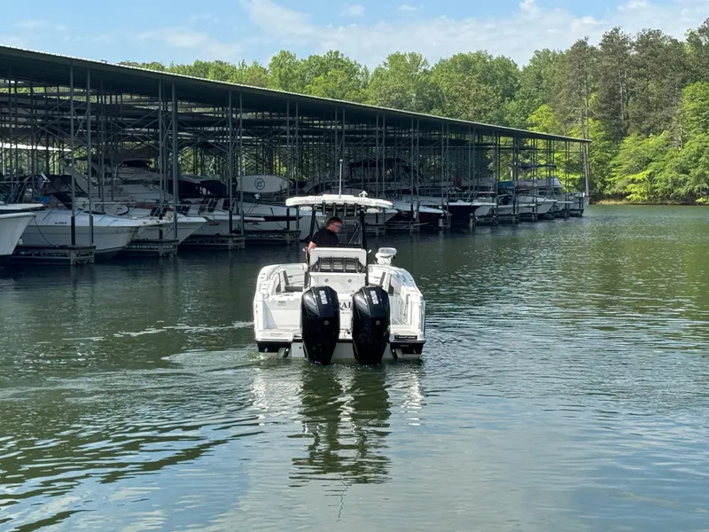 Slide: The Image of 2023 Blackfin 252 CC boat with dual engines near marina, surrounded by trees. - 5