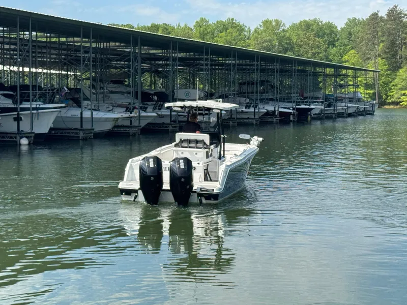 Slide: The Image of 2023 Blackfin 252 CC boat navigating near a marina with docked boats. - 6