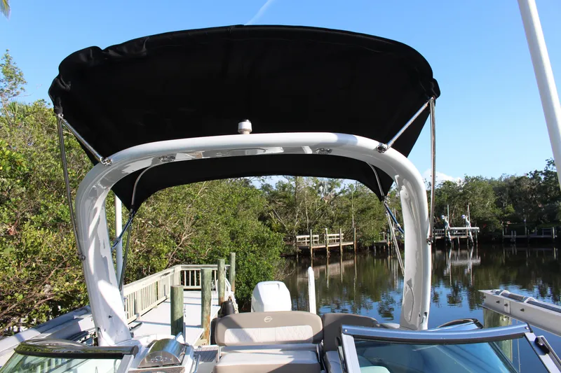 Slide: The Image of 2019 Crownline Eclipse E285 XS boat with black canopy docked by a scenic river. - 11