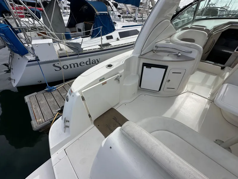 Slide: The Image of 2003 Sea Ray 320 Sundancer boat docked, featuring spacious white deck and seating area. - 10