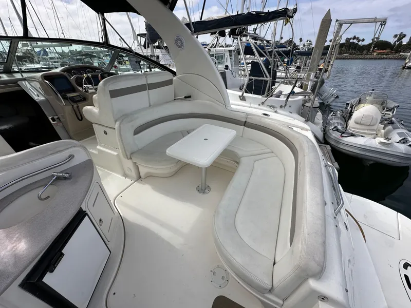 Slide: The Image of 2003 Sea Ray 320 Sundancer boat interior with white seating and table, docked at marina. - 11