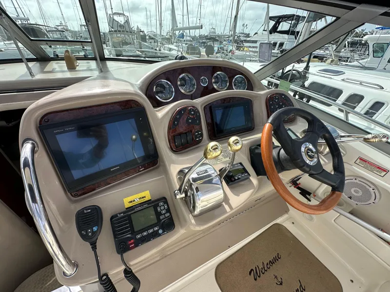 Slide: The Image of 2003 Sea Ray 320 Sundancer helm with navigation screens and controls at marina. - 17