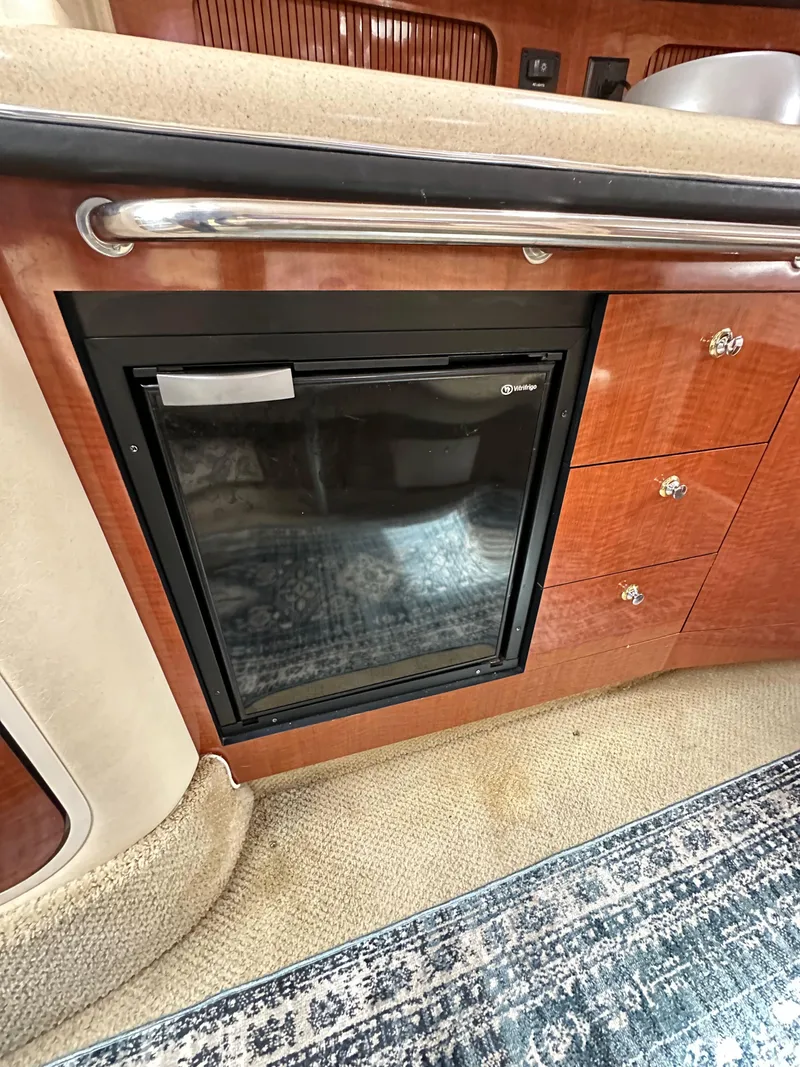 Slide: The Image of 2003 Sea Ray 320 Sundancer interior with wood cabinetry and built-in mini fridge. - 32