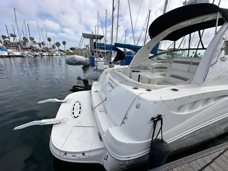 Slide: The Image of 2003 Sea Ray 320 Sundancer docked at a marina, showcasing sleek design and spacious deck. - 7