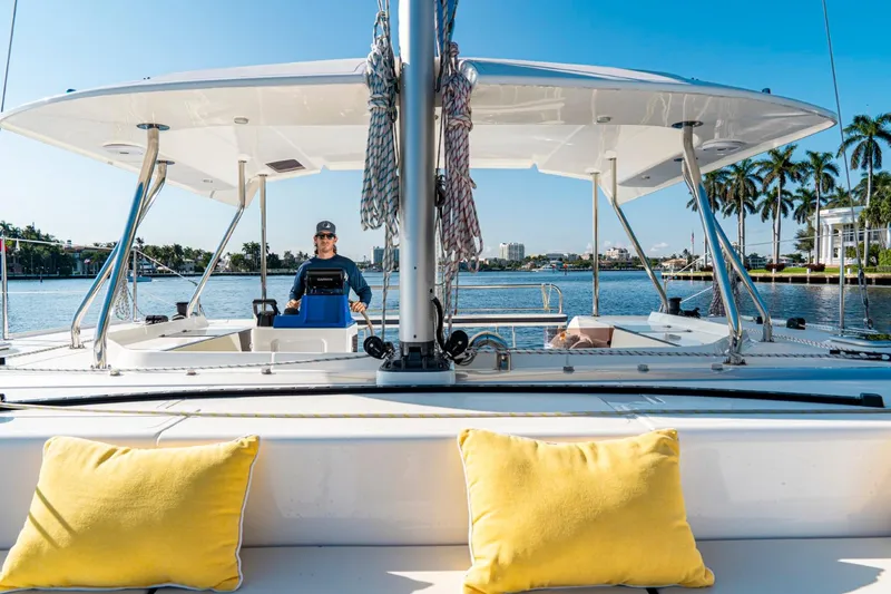 Slide: The Image of Person steering 2025 Smart Cat S280 catamaran on sunny day, with yellow cushions in foreground. - 13