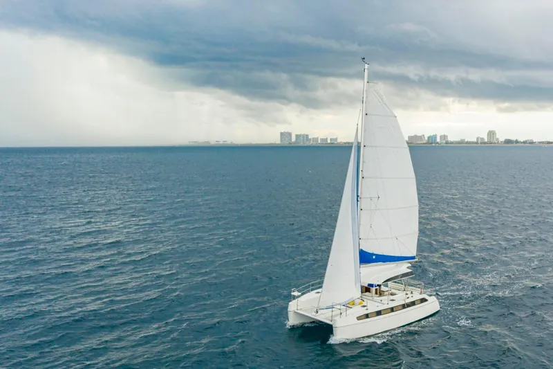 Slide: The Image of Sailing catamaran on open sea under cloudy skies, near city skyline. - 3