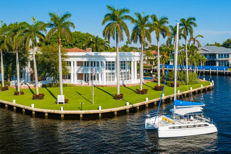 Slide: The Image of Luxurious waterfront mansion with palm trees and a Smart Cat S280 catamaran docked nearby. - 6