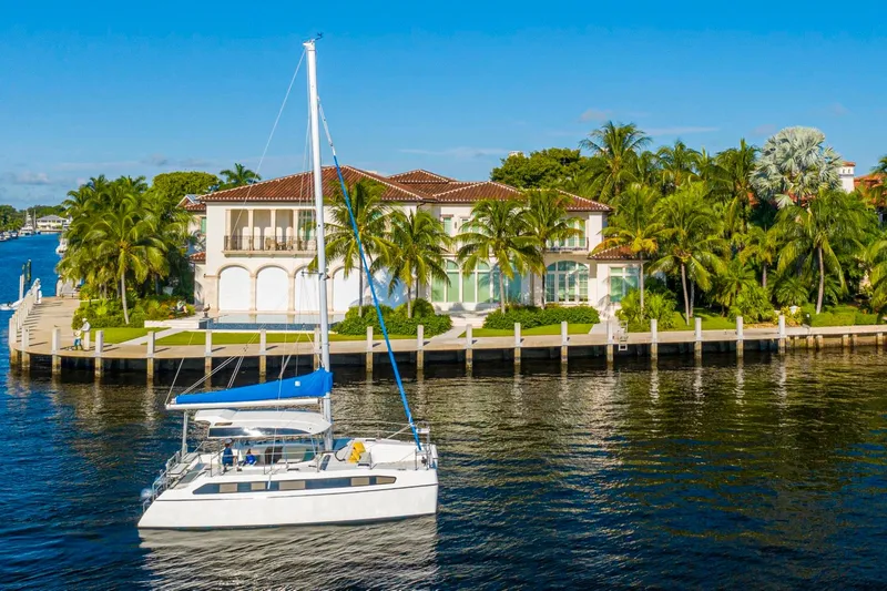 Slide: The Image of Luxury catamaran Smart Cat S280 sailing near waterfront mansion, surrounded by palm trees and clear blue sky. - 7