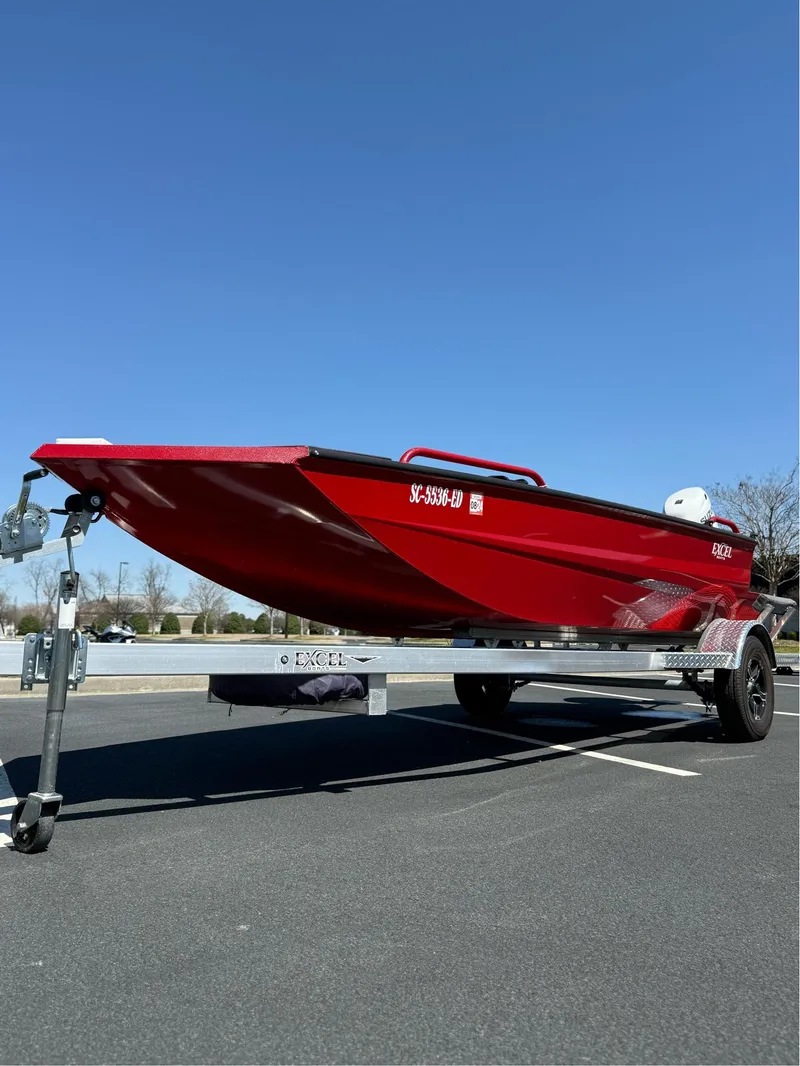Slide: The Image of Red 2024 Excel 1751 V4 boat on trailer under clear blue sky. - 13