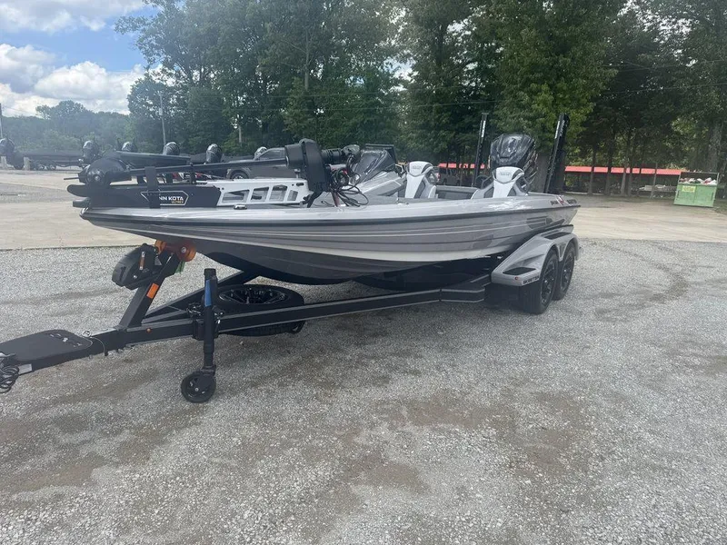 Slide: The Image of 2025 Skeeter FXR20L boat on trailer, parked outdoors, surrounded by trees. - 0