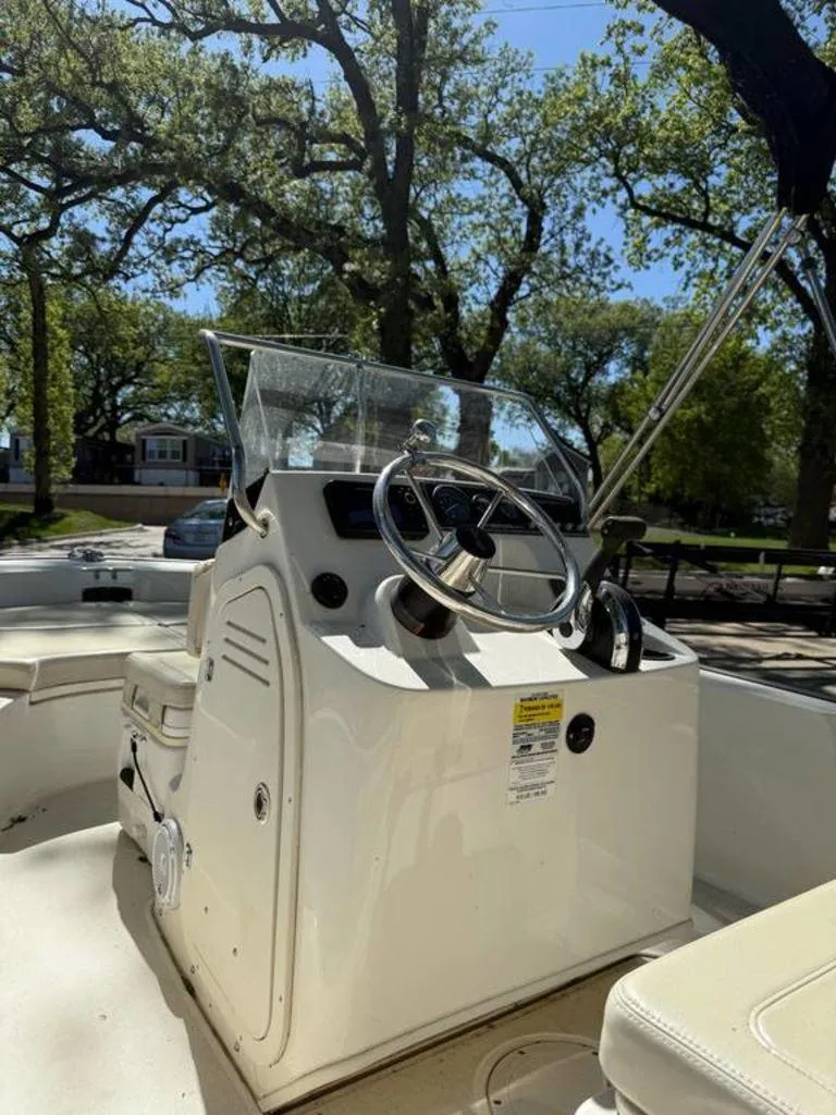 Slide: The Image of 2020 Boston Whaler 170 Montauk boat console with steering wheel, outdoors under trees. - 8