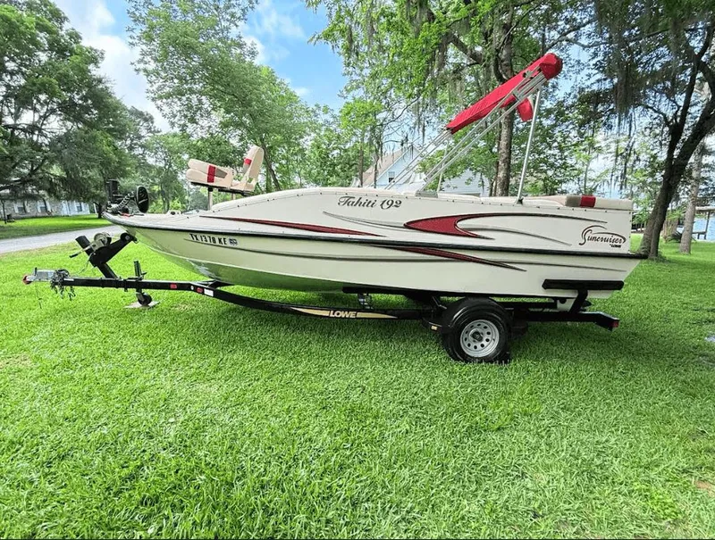 Slide: The Image of 2005 Lowe Suncruiser boat on trailer, parked on grass with trees in background. - 0