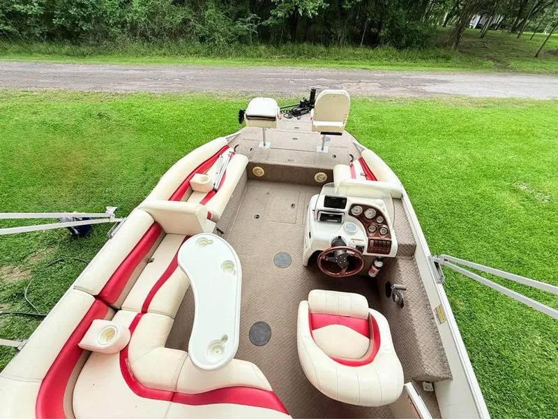 Slide: The Image of 2005 Lowe Suncruiser boat interior with red and white seating, steering console, and lush green surroundings. - 11