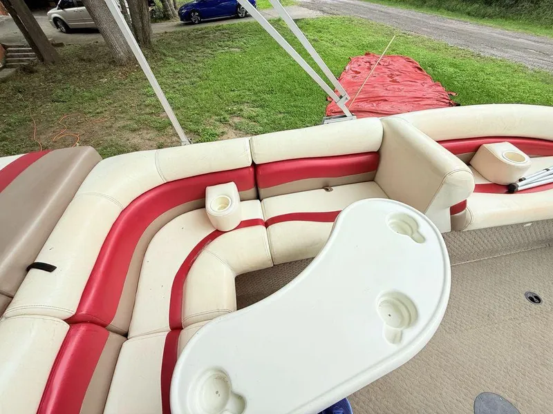 Slide: The Image of 2005 Lowe Suncruiser boat interior with red and beige seating, cup holders, and table. - 13