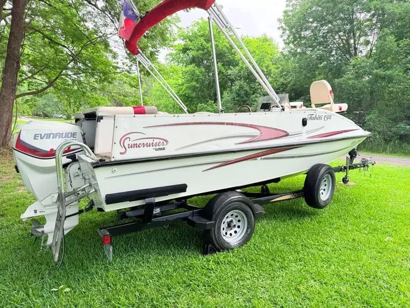 Slide: The Image of 2005 Lowe Suncruiser boat on trailer, parked on grass, surrounded by trees. - 2