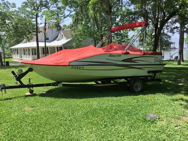 Slide: The Image of 2005 Lowe Suncruiser boat with red cover on trailer, parked on grassy lawn. - 4
