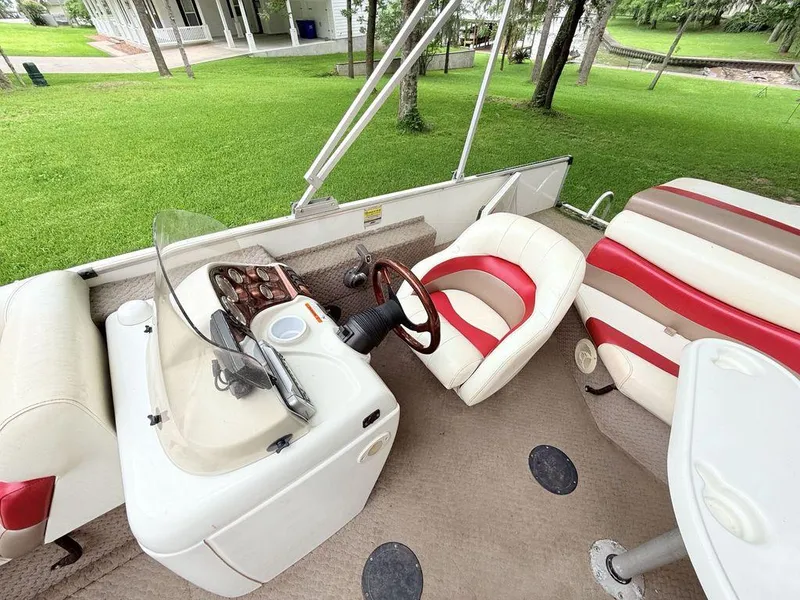 Slide: The Image of 2005 Lowe Suncruiser boat interior with red and white seating, steering console, and lush green surroundings. - 5