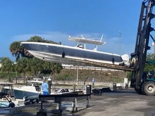 Slide: The Image of 2019 Intrepid 400 Center Console boat being lifted by a forklift at a marina. - 2
