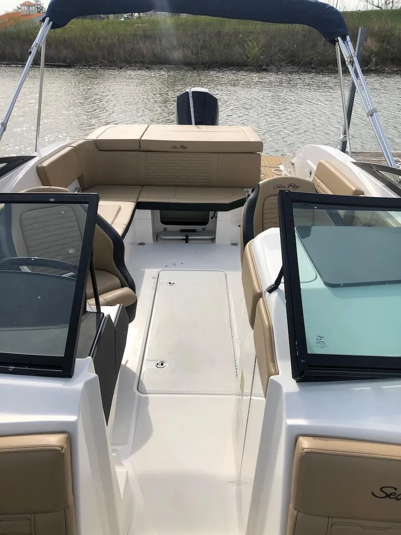 Slide: The Image of 2022 Sea Ray SPX 230 OB boat with tan seating and open deck on a calm waterway. - 9