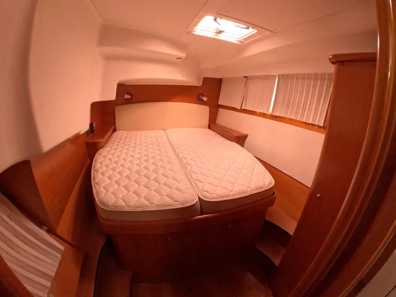 Slide: The Image of 2006 Lagoon 440 yacht cabin with double bed, wooden interior, and overhead hatch. - 13
