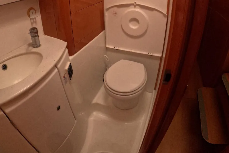 Slide: The Image of Bathroom interior of a 2006 Lagoon 440 yacht, featuring a compact toilet and sink. - 16