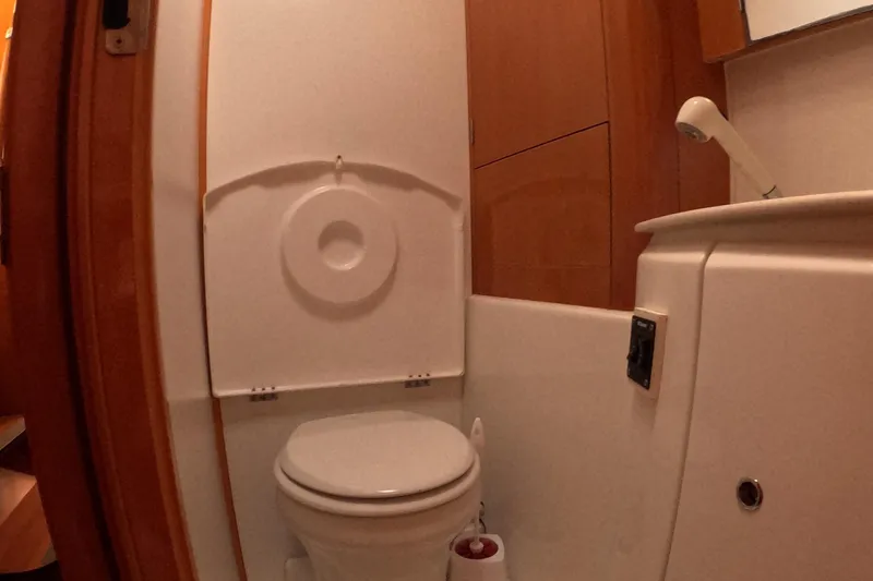 Slide: The Image of 2006 Lagoon 440 yacht bathroom with toilet and sink, compact marine design. - 19