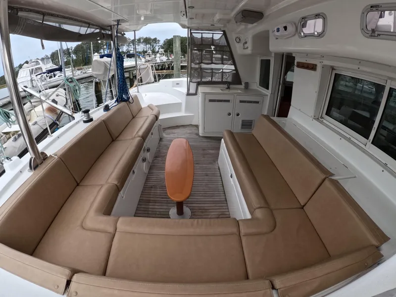 Slide: The Image of Spacious seating area on a 2006 Lagoon 440 catamaran, docked at a marina. - 23