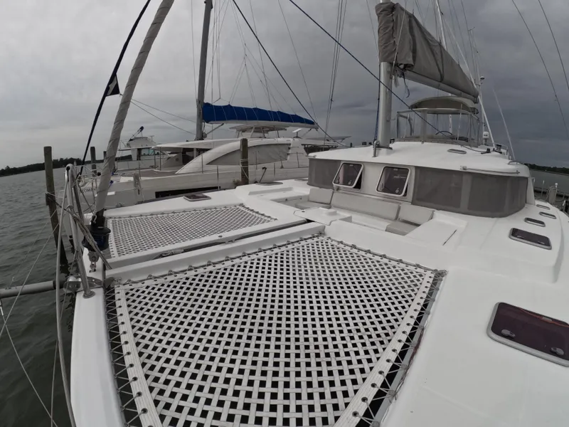 Slide: The Image of 2006 Lagoon 440 catamaran docked, featuring spacious deck and netting under cloudy skies. - 29