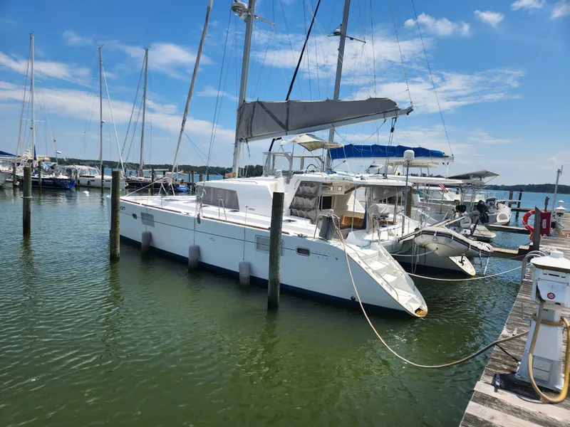 Slide: The Image of 2006 Lagoon 440 catamaran docked at a marina under a clear blue sky. - 3